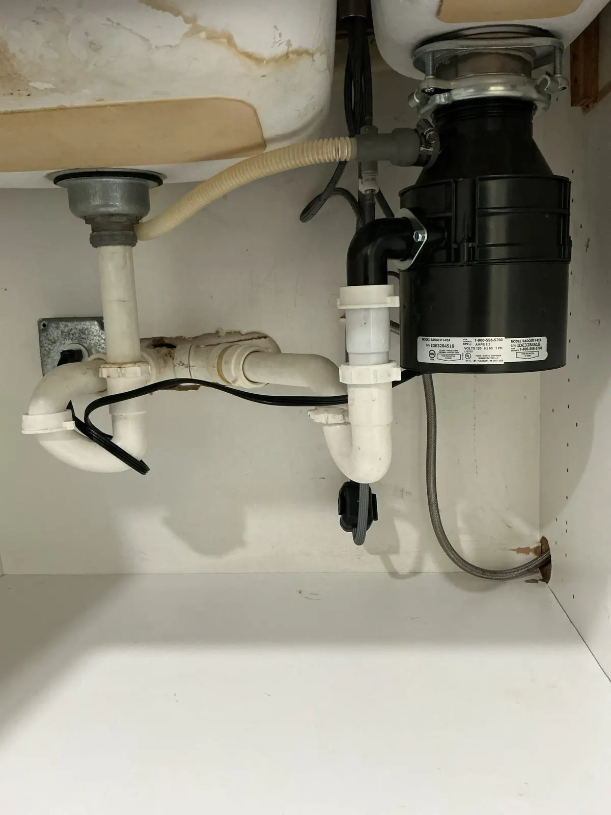 Plumber inspecting a garbage disposal under a kitchen sink