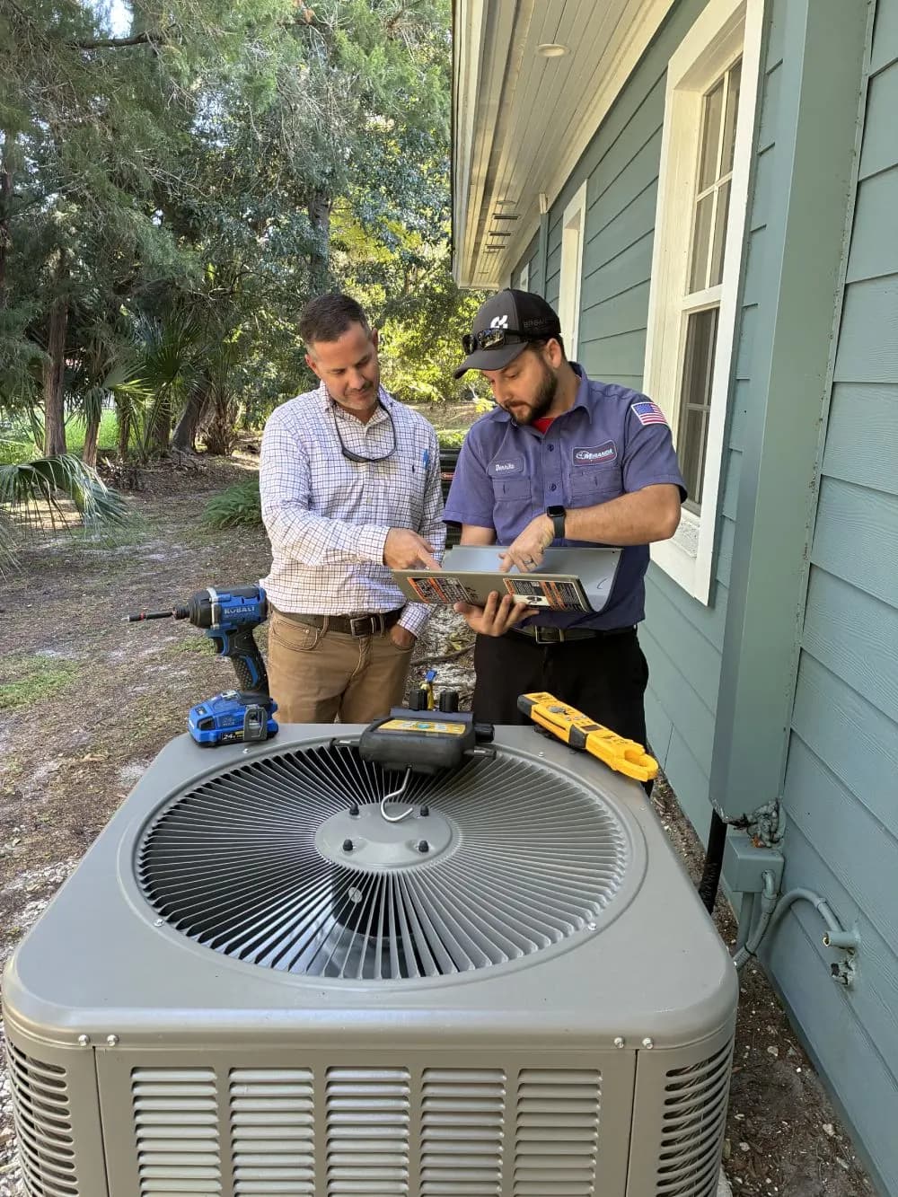 Miranda technician reviewing an outdoor air conditioning unit with a homeowner