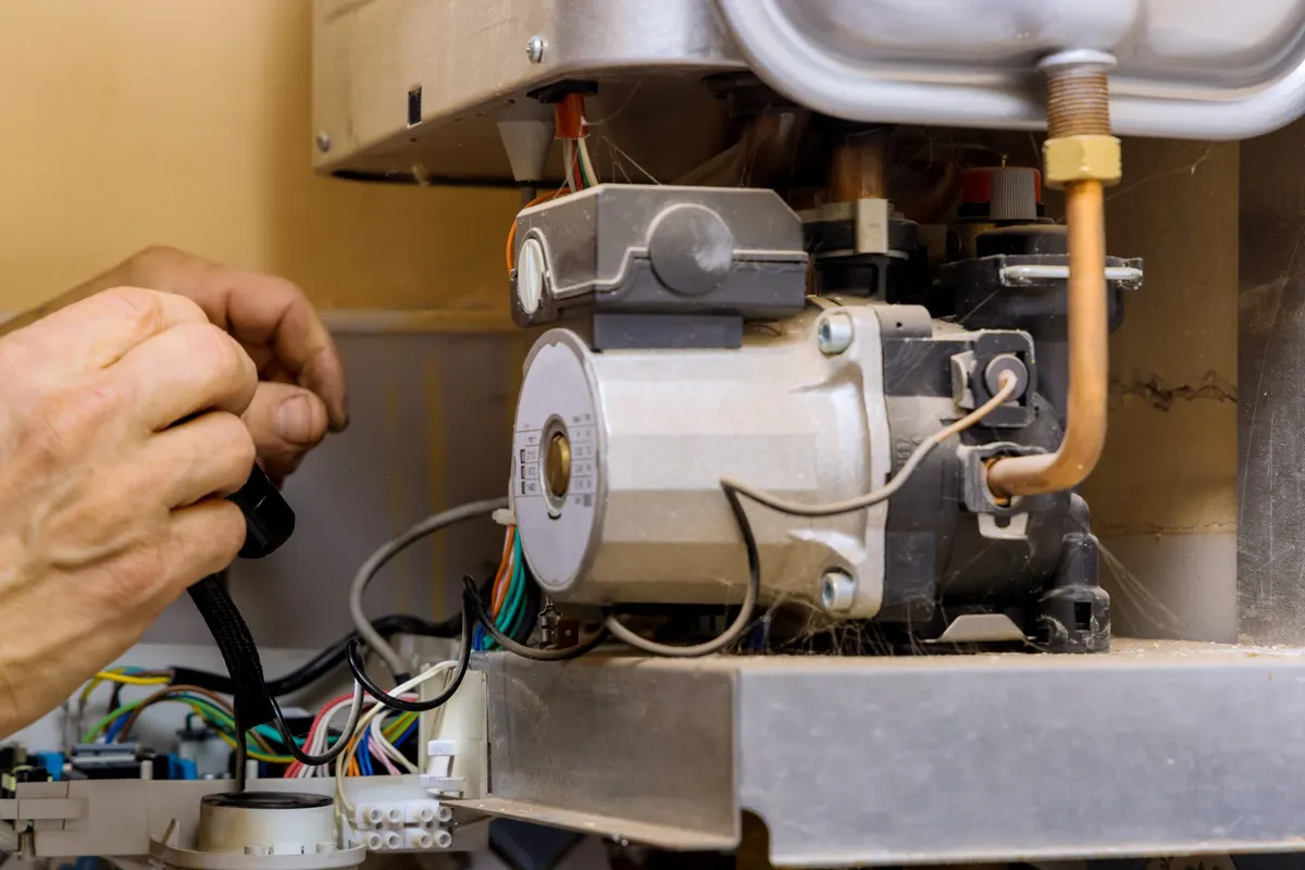 Technician diagnosing a water heater burner assembly