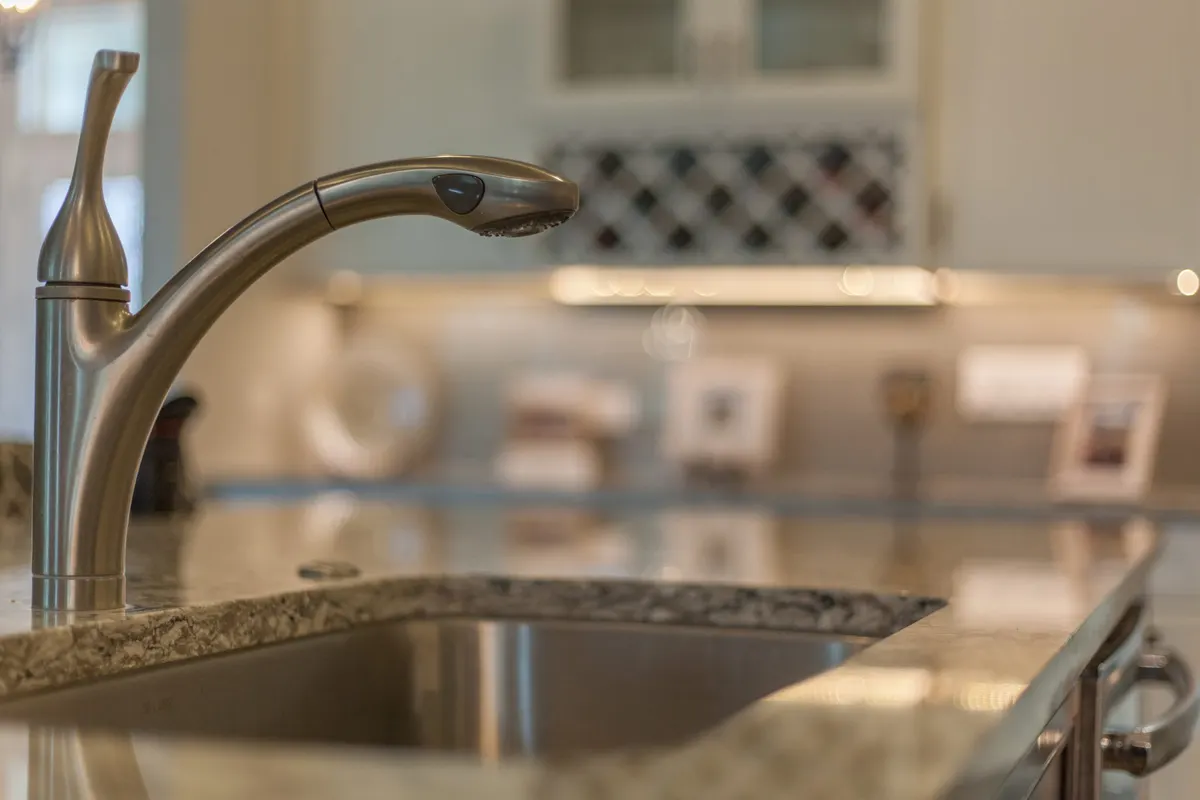Plumber removing a kitchen sink faucet