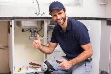 Plumber fixing under the sink in the kitchen